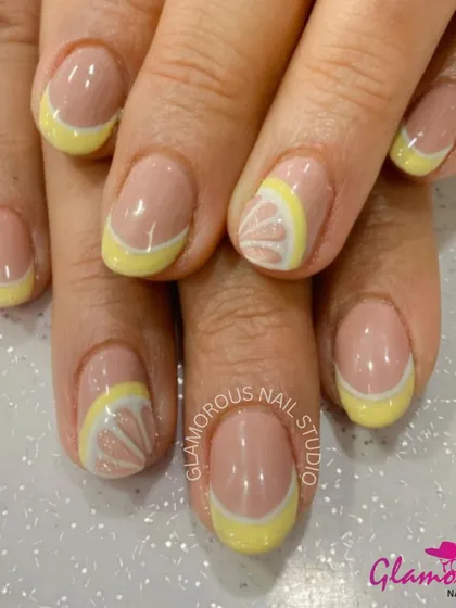 Squeeze the day with these zesty lemon-inspired nails. This design features a yellow French tip with an accent nail showing a detailed, hand-painted lemon slice.