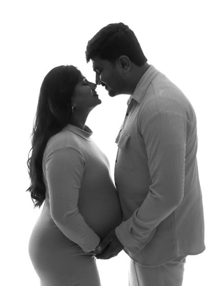 A high-contrast black and white silhouette. This style is modern and artistic, focusing on the loving shapes and outlines of the expectant couple.