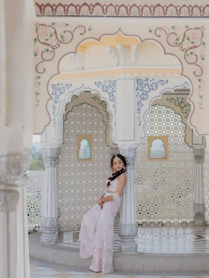 A picture of elegance. The bride is wearing our custom-designed sharara set with multi-color floral embroidery and mirror work, set against a beautiful heritage backdrop.