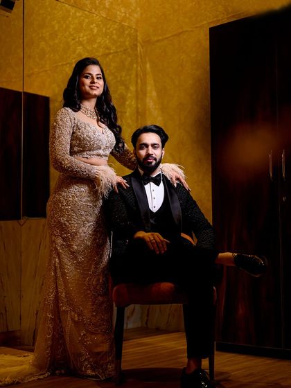 A classic, regal portrait of the couple, with the groom seated and the bride standing elegantly by his side.