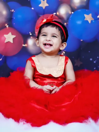 A beautiful, happy smile from the baby girl in her red dress and cloud-filled set.