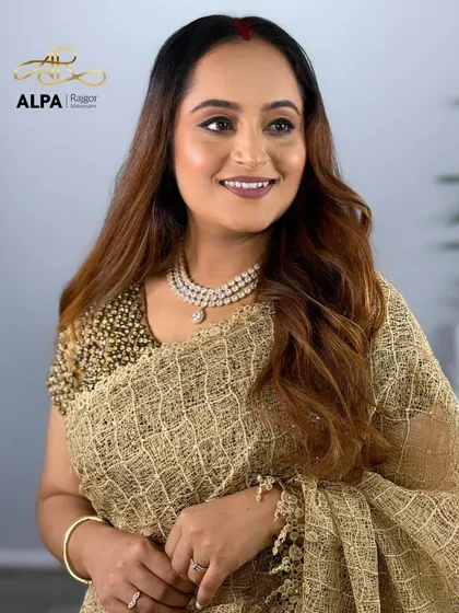 A smiling portrait in a golden saree. The makeup is soft and glowing, perfect for an elegant evening event.