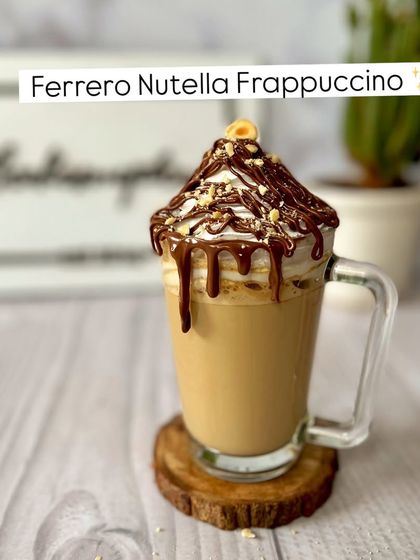 A close-up of the decadent Ferrero Nutella Frappuccino. Topped with whipped cream, chocolate drizzle, and a hazelnut, it's a dream come true for chocolate and coffee fans.