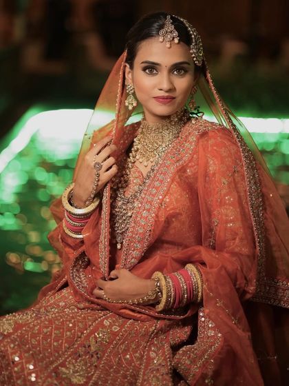 A stunning portrait of the bride, with the lighting highlighting her flawless makeup and the intricate details of her Passa (side tikka).