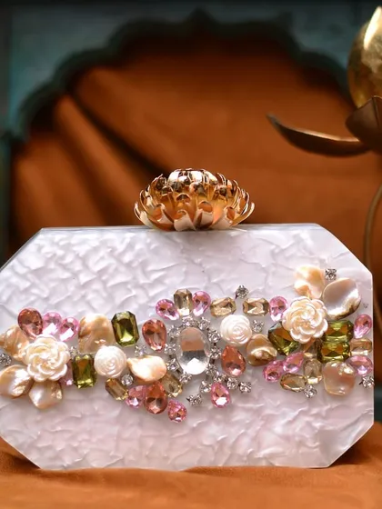 For a touch of modern glamour, I offer these beautiful acrylic clutches. This one has a pearlescent white finish and is hand embellished with 3D floral details and sparkling rhinestones, topped with a golden lotus clasp.