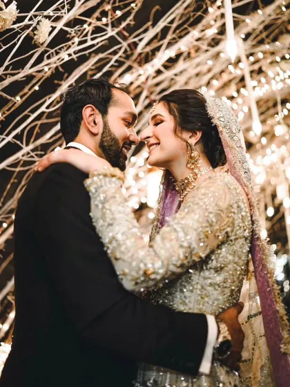 A romantic, candid moment between the couple at their reception. Their smiles and embrace under a tunnel of lights show their happiness.
