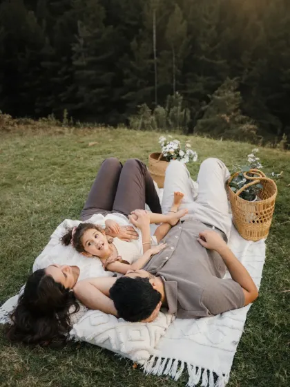 A family relaxes on a blanket in a wide-open field. This overhead shot captures a peaceful, connected moment during their outdoor session.