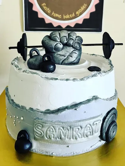 A cake designed for a fitness enthusiast. This gym-themed cake is topped with handcrafted fondant weights, a kettlebell, and a fist, all on top of my signature chocolate cake.
