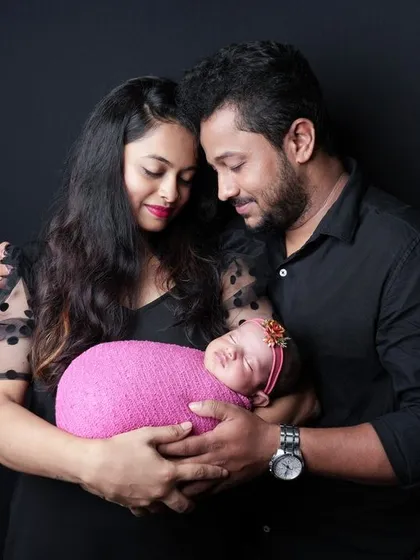 A loving portrait of a new family, with the baby girl wrapped in a bright pink swaddle that coordinates with her mother's dress. These shots capture the joy and tenderness of welcoming a new baby.