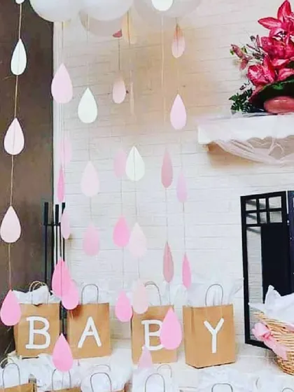 A close-up of my 'Simple n Shower' baby shower theme. This creative setup includes paper raindrops hanging from above and custom paper bags spelling out 'BABY', perfect for holding gifts or party favors.
