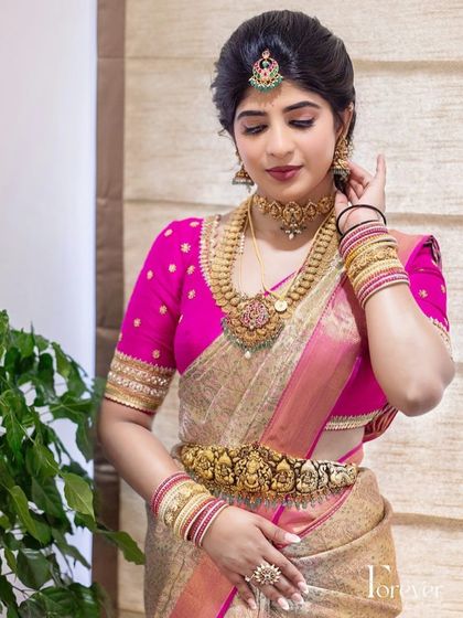 A classic combination of a gold tissue saree with a bright pink blouse. The blouse features simple butti embroidery, adding just the right amount of detail to the ensemble.