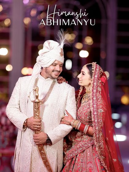 A stunning night-time portrait of the couple, "Himanshi & Abhimanyu." The groom holds a traditional sword (kirpan), and the soft bokeh of the background lights adds a magical touch to this regal shot.