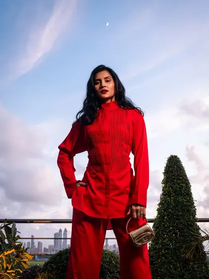 A full-length shot of my red outfit against the evening sky and the Mumbai skyline, with the moon making a guest appearance.