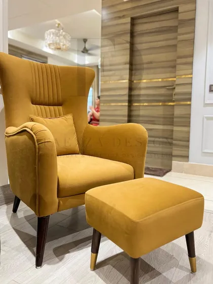 A mustard yellow wingback chair with a matching ottoman. The chair features subtle vertical tufting on its back, adding a touch of texture to its clean, modern lines.