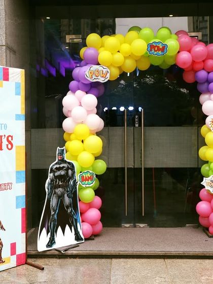 A superhero-themed entrance for Ivaan's 9th birthday, featuring Batman and Iron Man cutouts and a colorful balloon arch.