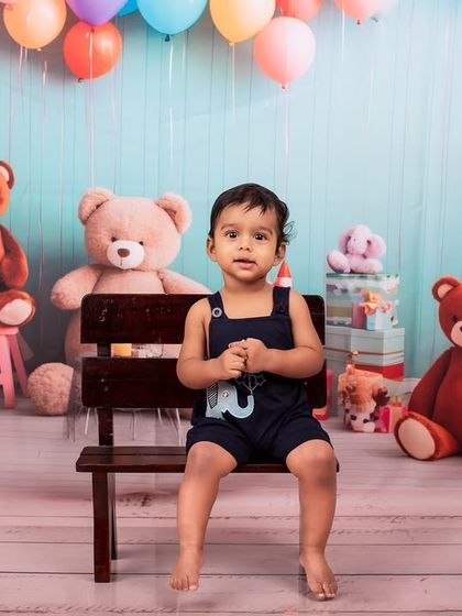 A classic portrait before the cake smash begins. The number '1' prop and the adorable teddy bear backdrop set the stage for a perfect first birthday celebration.