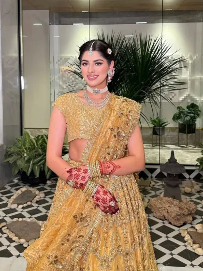 A full-length shot capturing the grandeur of this golden lehenga. The dupatta is draped elegantly to showcase the detailed blouse and skirt.