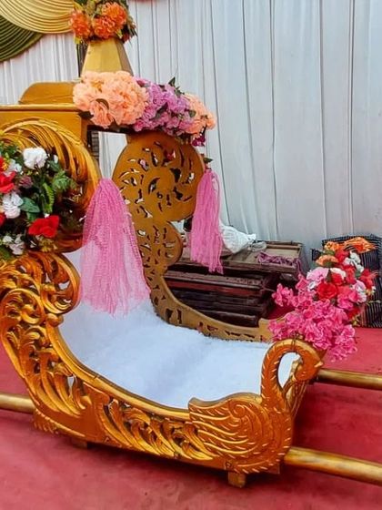 Another look at the golden swan doli, decorated with flowers for a wedding. The handles are sturdy, ensuring a smooth and safe ride for the bride.