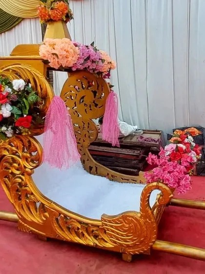 A golden swan-themed Palki, perfect for a traditional bridal entry. This rental is elegantly carved and can be decorated with flowers to match your wedding colors.