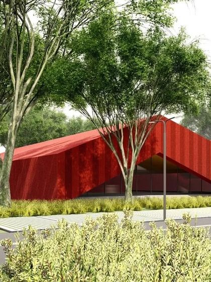 The red building seen nestled among trees, demonstrating how even bold, abstract forms can be integrated thoughtfully into a natural setting.