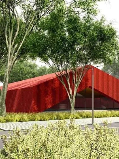 The red building seen nestled among trees, demonstrating how even bold, abstract forms can be integrated thoughtfully into a natural setting.