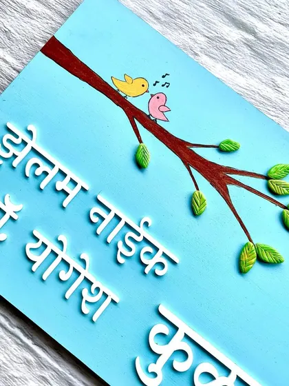 A close-up of the hand-painted birds on a branch, adding a sweet and personal touch to this Marathi nameplate.