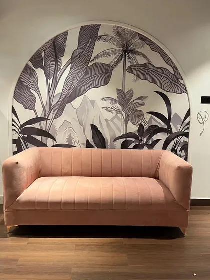 Arched nooks provide a perfect frame for a wallpaper accent. Here, a monochrome tropical mural behind a pink sofa creates a stylish and well-defined seating area.