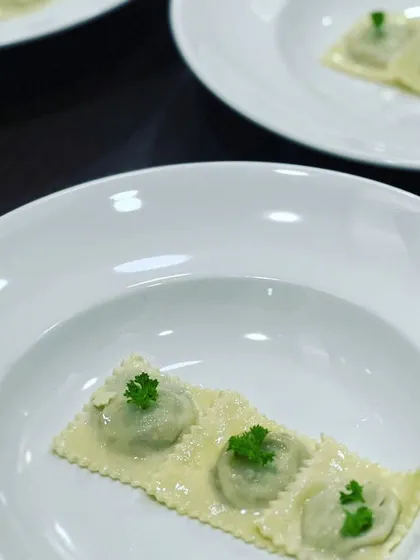 The first course of a sit-down meal: delicate, handcrafted ravioli, simply garnished with parsley, showcasing our focus on quality ingredients.