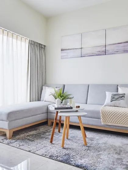 This living room from our 'Nordic Nest' project is a tranquil sanctuary defined by Scandinavian design principles. The light grey sofa, sheer curtains, and natural wood accents come together to create a bright, airy, and calming atmosphere.