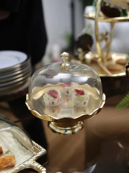 Our small golden dessert stand with a glass cloche, showcasing delicate cupcakes. This piece adds a touch of drama and elegance, making even the smallest treats feel special.