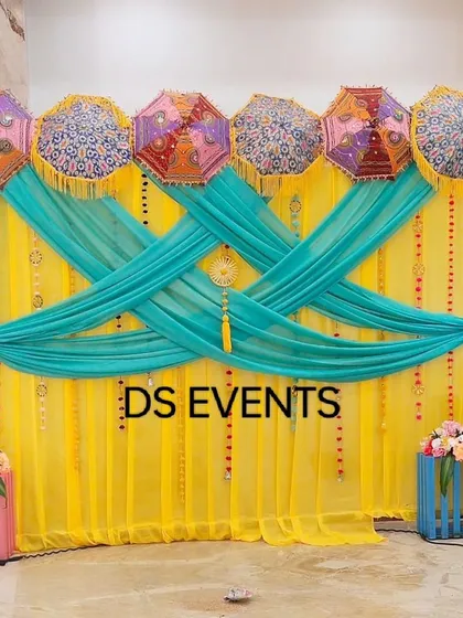 A colorful and festive photo booth corner for a Mehendi event. I used a bright yellow backdrop with turquoise drapes and decorated it with traditional Rajasthani embroidered umbrellas to create a fun and vibrant space for guests.