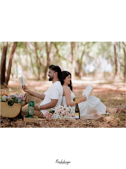 A wide shot of a couple enjoying a picnic setup in a forest clearing, perfect for showcasing a relaxed and romantic theme.