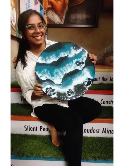The joy of creation. A smiling student presents her finished ocean-themed resin art, a testament to her newfound skills.
