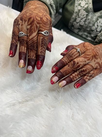 Another view of the red and gold bridal art on natural nails. The design is carefully placed to complement the flow of the mehndi, creating a harmonious and elegant look.