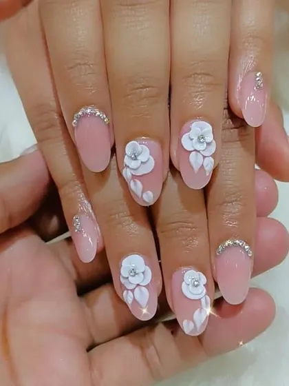 For a more subtle bridal look, we created these soft pink nails with delicate 3D white flowers and rhinestone details at the cuticle.