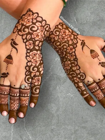 A beautiful back-of-hand design featuring a floral vine with birds and hanging jhumkas. It's a classic pattern that is always a popular choice for wedding guests.