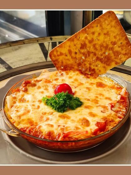 Our baked lasagna is a crowd favorite. It's cheesy, authentic, and served with a crispy garlic bread cracker, making for a hearty and comforting meal.