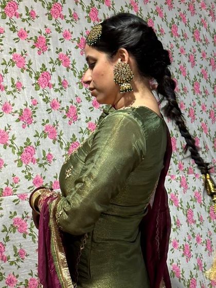 A side profile showcasing the traditional hairstyle with a parandi and the statement earrings, which complete this classic Punjabi look.