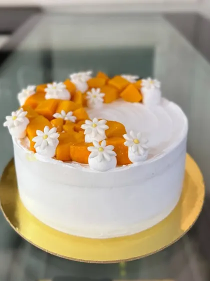 A side view of the fresh mango and daisy cake.