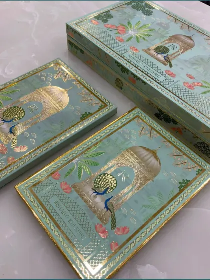 The complete wedding invitation box set, highlighting the consistent and regal peacock design on both the main box and the individual sweet boxes inside.