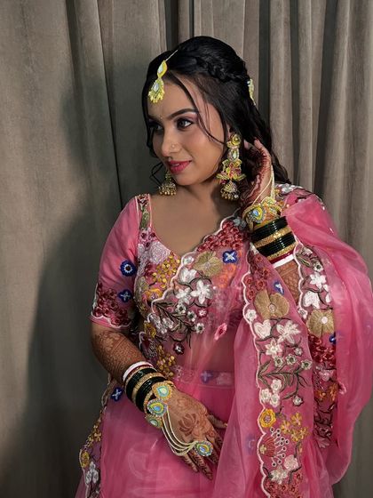 The bride's full Haldi look, with a pink embroidered lehenga and unique floral-style jewellery.