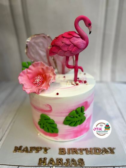 A tropical and elegant flamingo cake. This design features a pink marble buttercream, edible leaves, and a beautifully crafted fondant flamingo.
