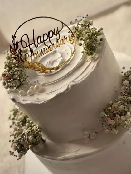 A simple and elegant two-tier anniversary cake. The clean white frosting is beautifully complemented by delicate sprigs of baby's breath.