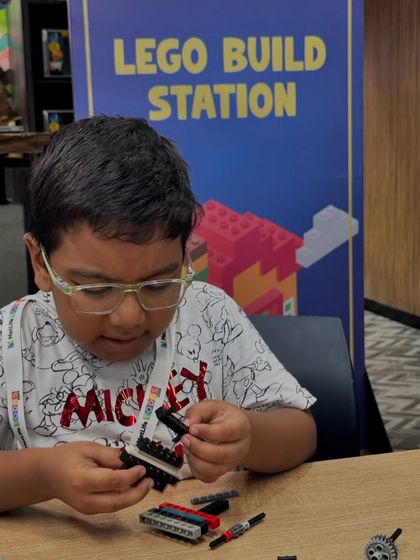 A student focuses on his project at the LEGO Build Station. These open-ended building activities encourage creativity and engineering thinking as kids assemble parts to create their own unique models.