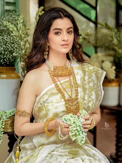 Actress Darshana Banik in a beautiful white and gold saree for a Sananda cover shoot. The composition, filled with white flowers, creates a fresh and elegant look perfect for a New Year edition.