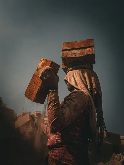 A woman carries her load at a brick kiln, her form silhouetted against the sky. This image is from my long-term project documenting the strength and dignity of laborers who build our world one brick at a time.