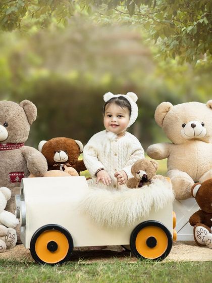 A close-up of the birthday girl in her teddy bear car. The soft, natural light of an outdoor shoot creates a beautiful, warm glow.