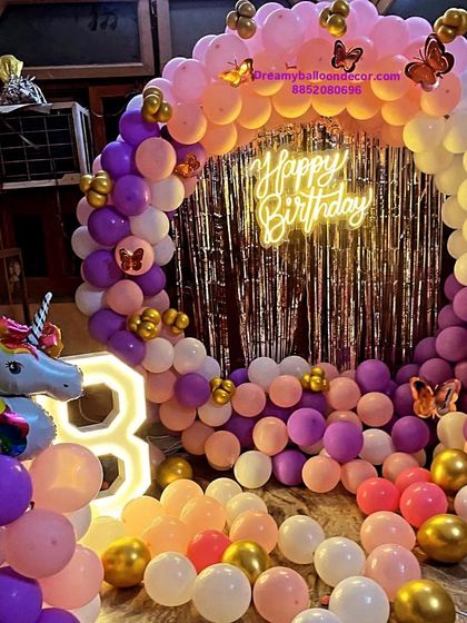 A grand unicorn and butterfly themed decoration for a 3rd birthday. This setup includes a full balloon ring, a large light-up marquee number, and a unicorn foil balloon, creating a magical atmosphere.