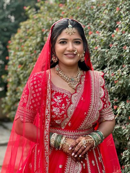 A classic red lehenga look for a beautiful bride. The makeup is kept clean and radiant, with a focus on flawless skin and defined features that stand out against the vibrant red.