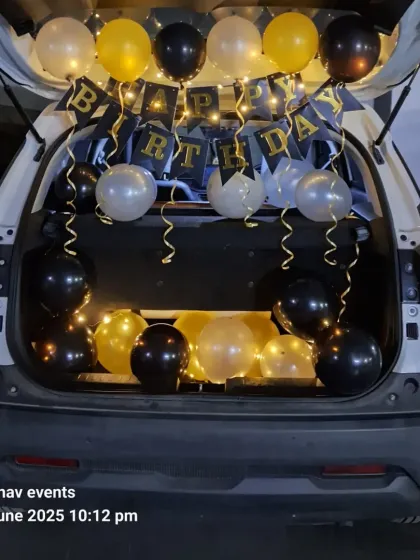 A car boot or dickey decoration is a great way to surprise someone. This setup includes a 'Happy Birthday' banner, fairy lights, and balloons in black, gold, and silver, creating a perfect movie-style surprise moment.